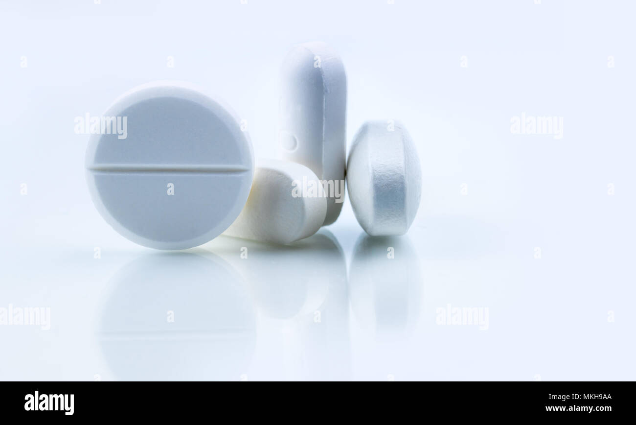 Pila di round bianco e di forma oblunga tablet pillole isolati su sfondo bianco. Industria farmaceutica. Farmacia farmacia o simbolo e segno. Global Foto Stock
