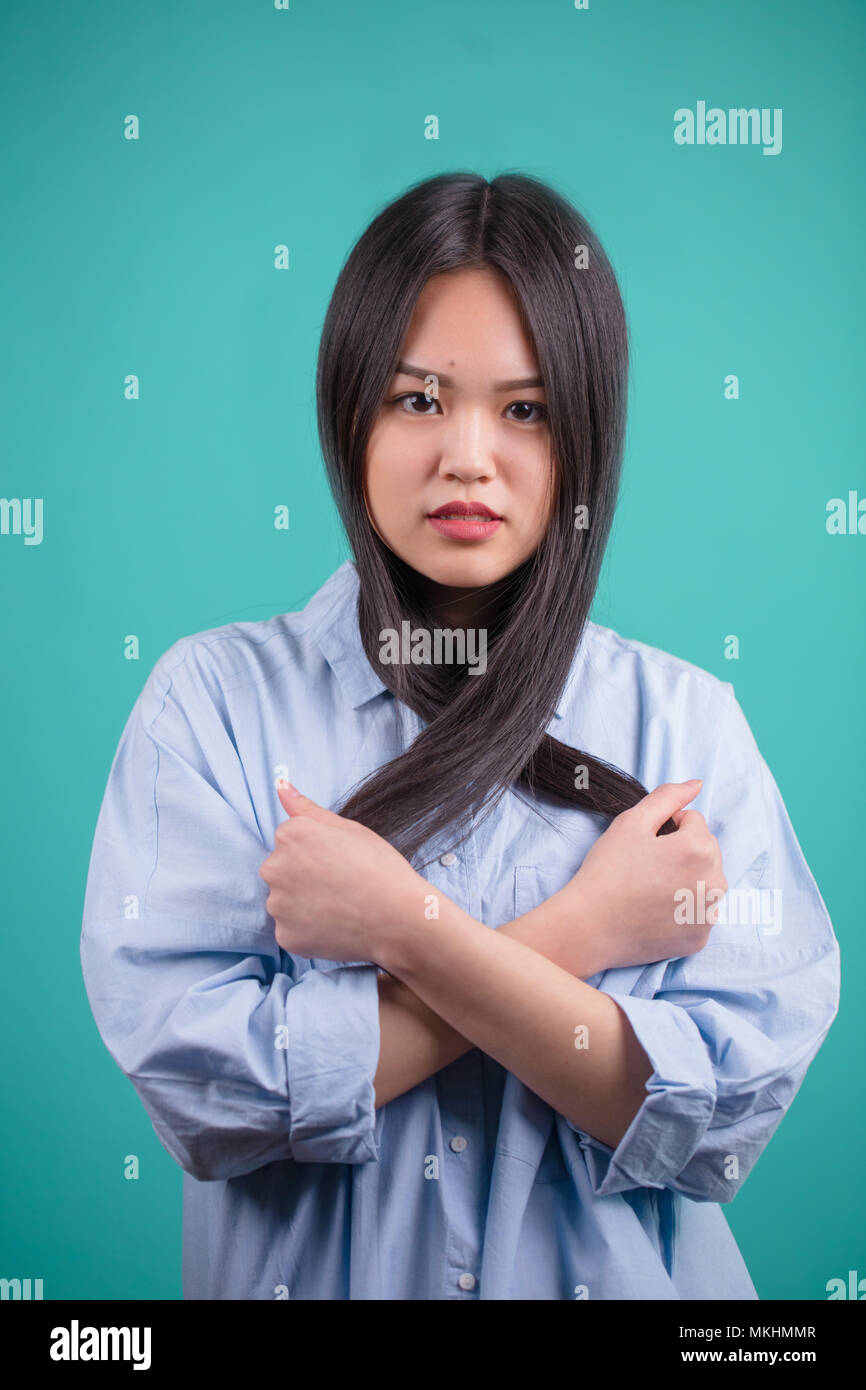 Un aspetto naturale giovani asiatici donna con i capelli perfetti per collocare in un modo incrociato isolato blu su sfondo azzurro Foto Stock