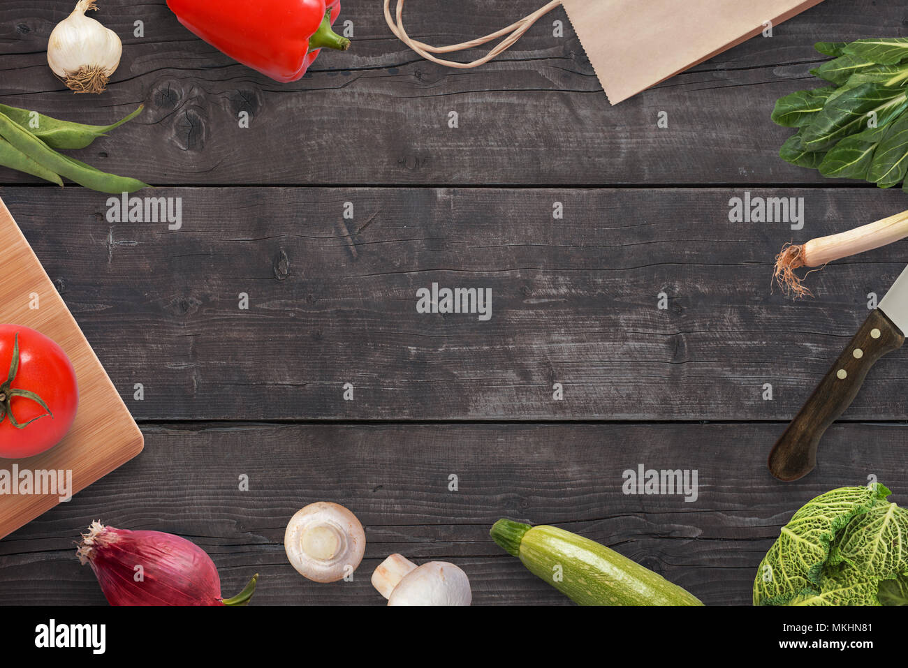 Preparazione di pasti su un tavolo da cucina con un sacco di verdure. Nero scrivania in legno con spazio libero per il testo in background. Foto Stock