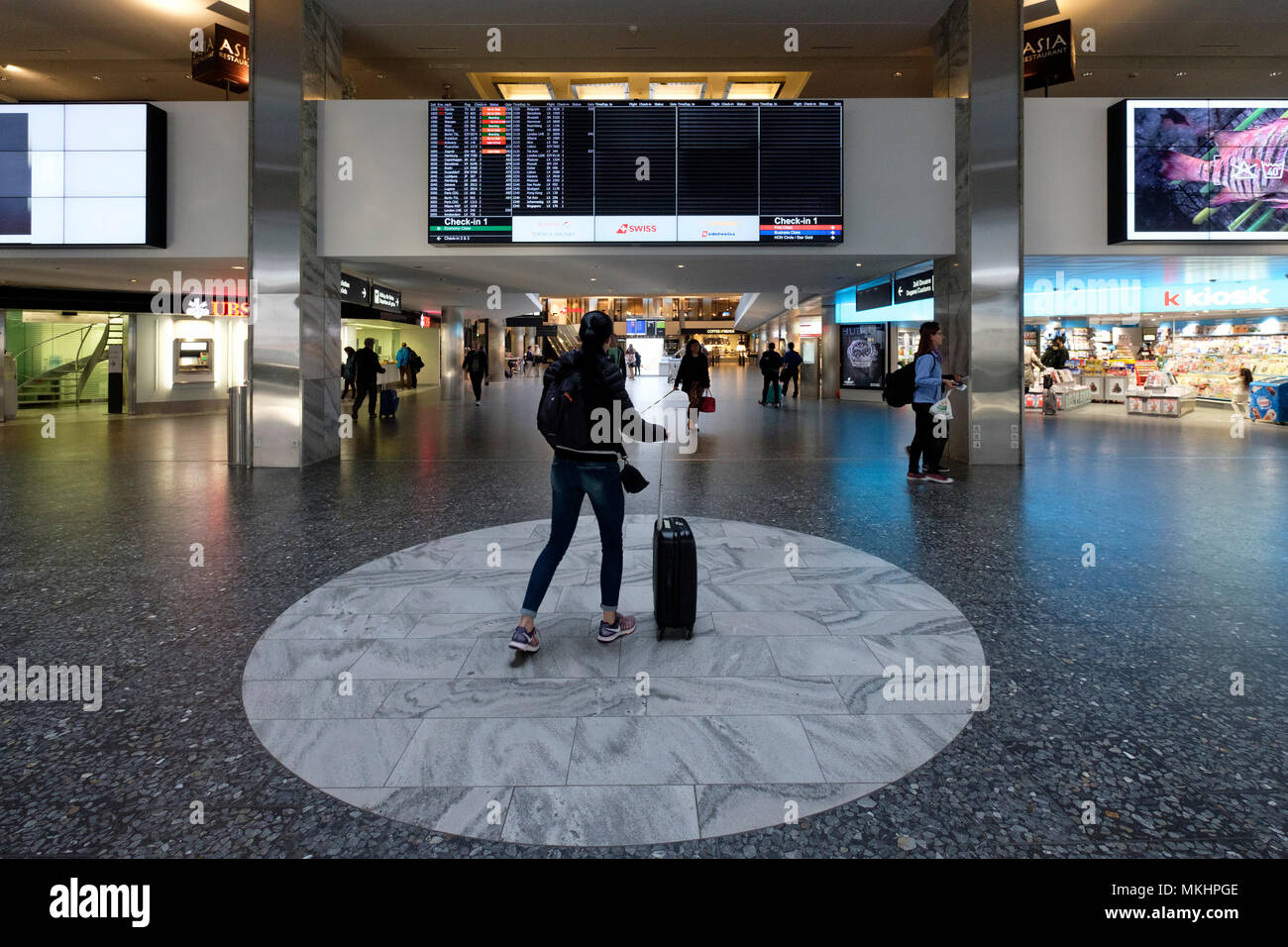 Viaggiatori femmina a piedi attraverso l'aeroporto di Zurigo con una valigia scorrevole, Zurigo, Svizzera, Europa Foto Stock