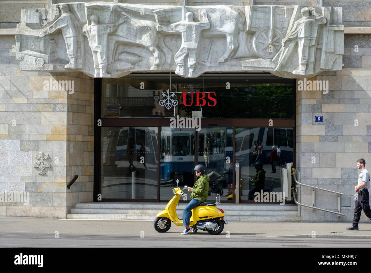 Un uomo su uno scooter giallo parcheggiato di fronte a una filiale UBS ufficio a Zurigo, Svizzera, Europa Foto Stock