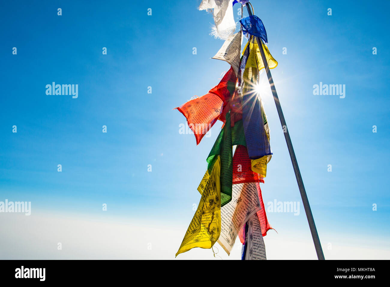 Vista ravvicinata di alcuni colorati Bandiere tibetane illuminata da una bella giornata di sole con un cielo blu. Foto Stock