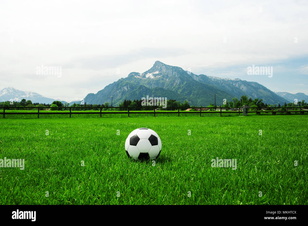 Classico bianco e nero pallone da calcio in erba naturale di fronte a una montagna di Salisburgo, Austria Foto Stock