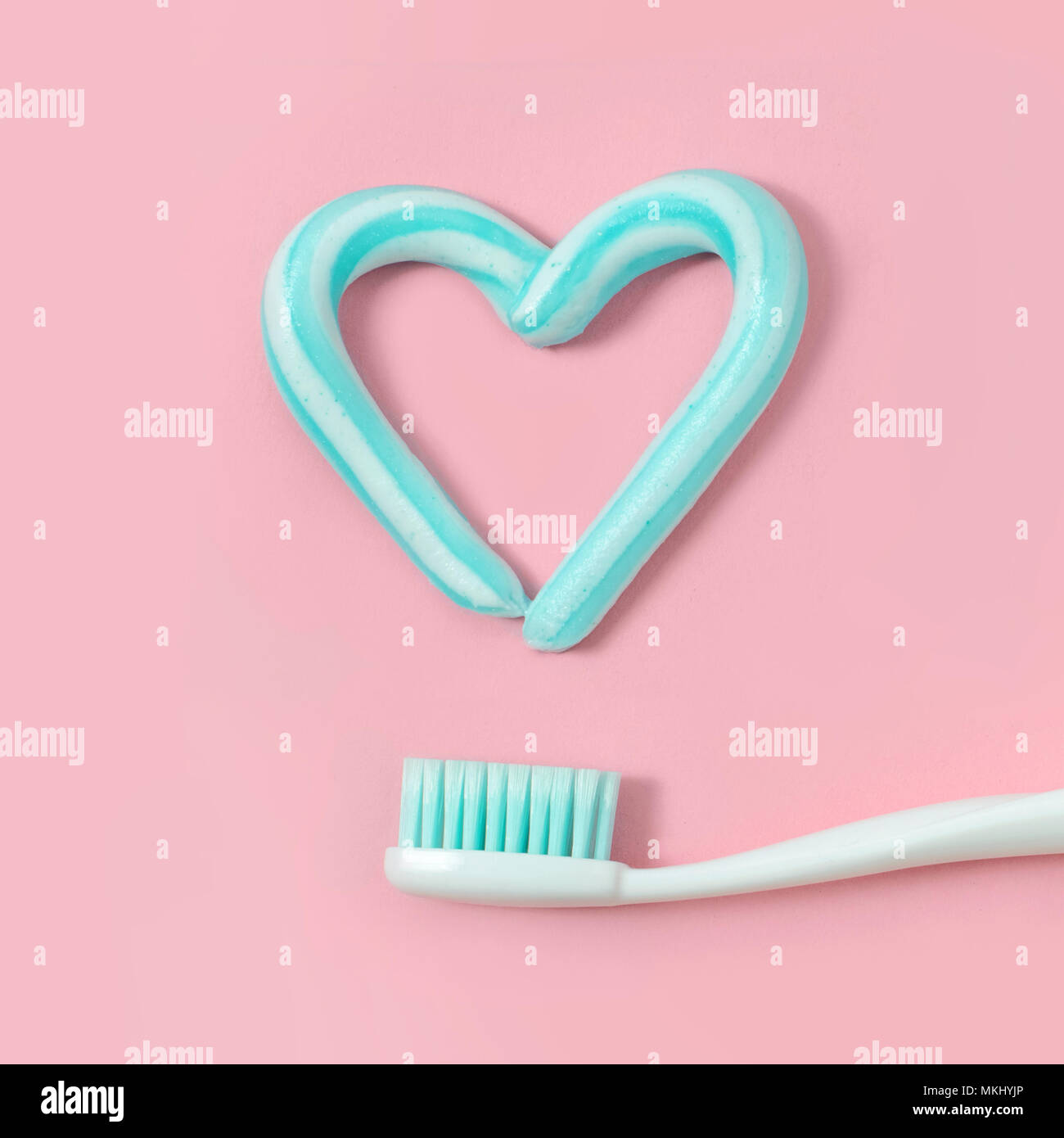 Gli spazzolini da denti e colore turchese il dentifricio a forma di cuore su sfondo rosa. Dentale e concetto di assistenza sanitaria. Foto Stock