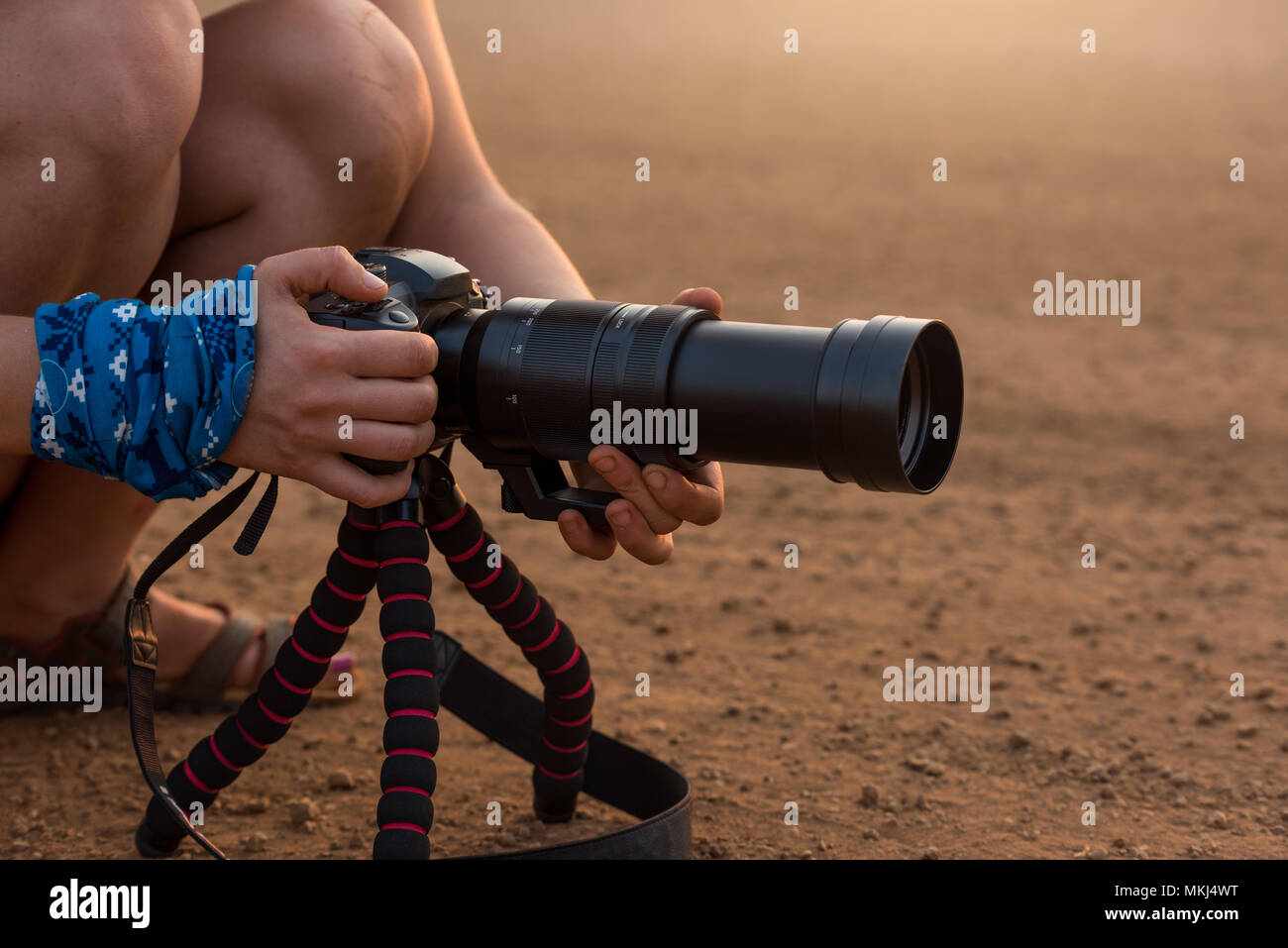 Operatore di ripresa la preparazione di fotocamera DSLR con grande lente per le riprese in gloria di pomeriggio di luce. Foto Stock