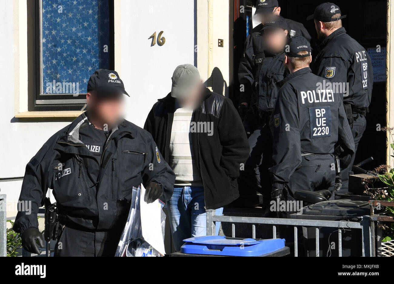 08 maggio 2018, Germania, Bremen: poliziotti scortare un uomo arrestato da una casa ad un auto di pattuglia. La polizia tedesca ha lanciato una larga scala di anti-contrabbando di persone il funzionamento con 800 funzionari di polizia che partecipano in incursioni in appartamenti e uffici nella parte settentrionale e centrale in Germania. La ragione per le incursioni è il sospetto di commerciali e pista-basato la tratta degli stranieri. Foto: Carmen Jaspersen/dpa - ATTENZIONE: individuale(i) è/sono stato disturbato per motivi legali Foto Stock