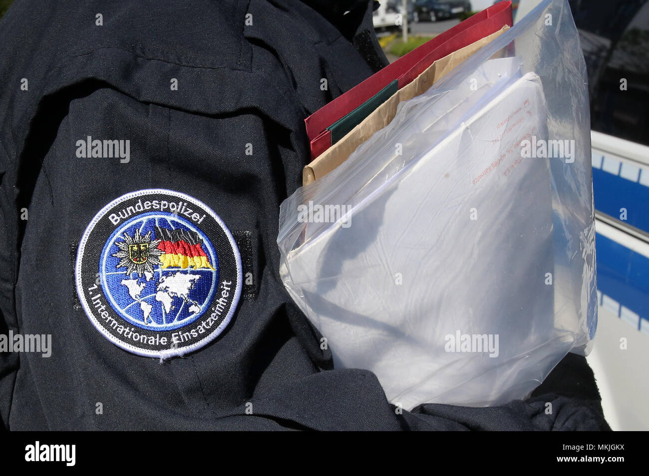 Bremen, Germania. 08 maggio 2018, Germania, Bremen: un funzionario di polizia porta prove confiscati in un auto di pattuglia. Una pista è sospettata di traffico di centinaia di moldavi in Germania e che impiegano illegalmente in servizi di sicurezza. Foto: Bodo segna/dpa Credito: dpa picture alliance/Alamy Live News Foto Stock