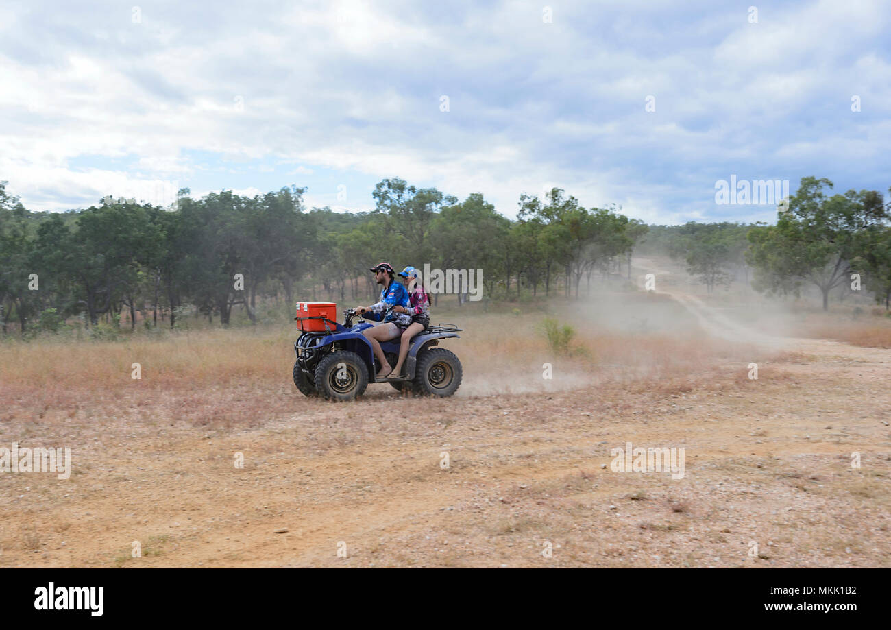 Coppia giovane a cavallo di un quadbike su backcountry sterrati con polvere battenti, Maytown, estremo Nord Queensland, FNQ, QLD, Australia Foto Stock
