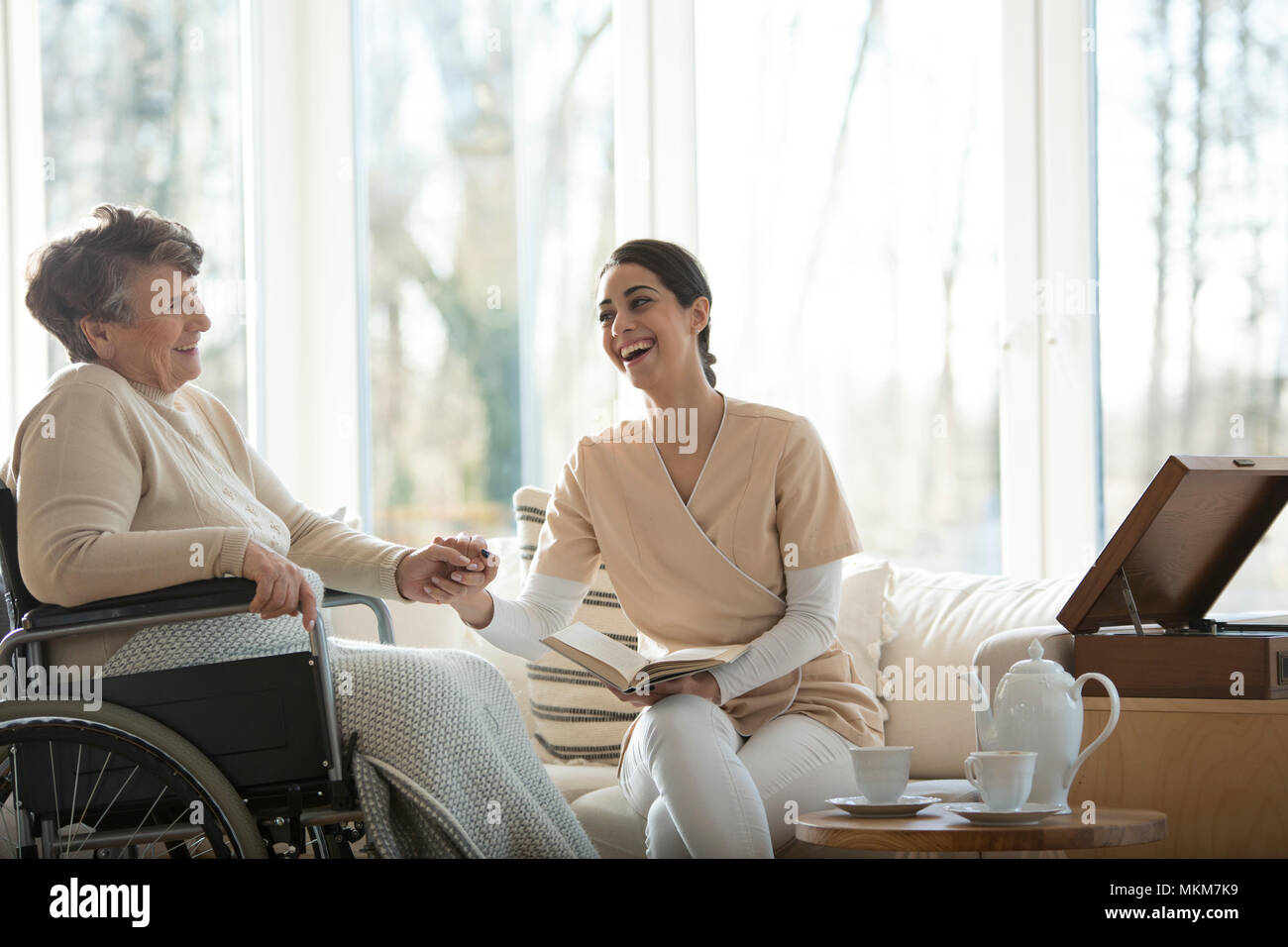Buon rapporto tra infermiere sorridente e felice anziani disabili donna nella casa di cura Foto Stock