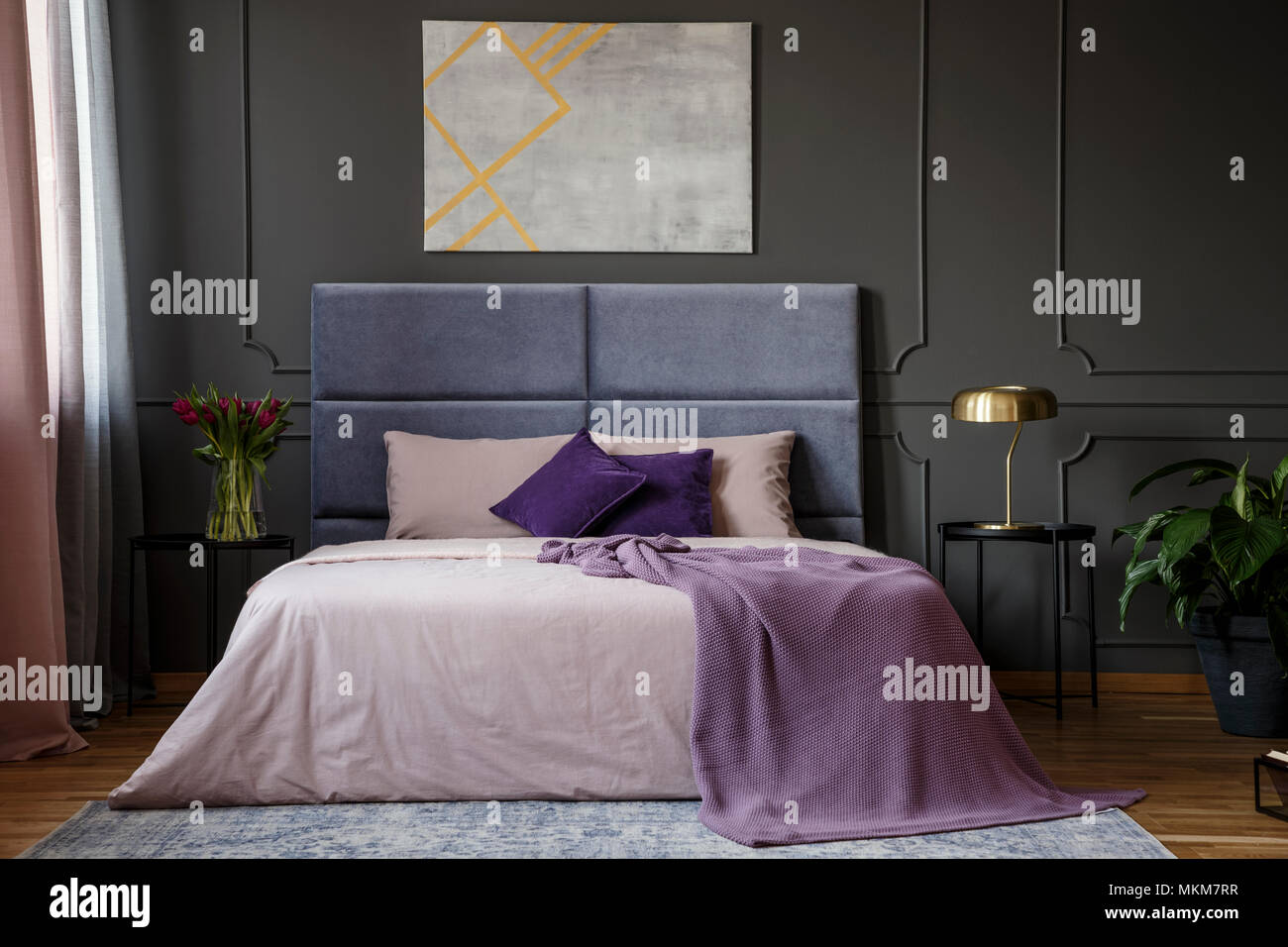 Violetta coperta del letto in camera da letto in colori pastello con interni grigio poster sul muro grigio con lo stampaggio Foto Stock