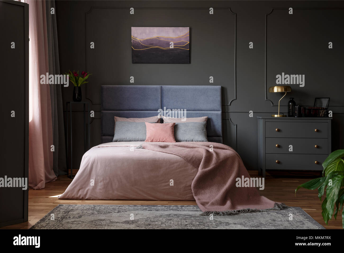 Coperta di pastello sul letto in rosa e in blu interiore camera da letto con lampada oro su cabinet grigio Foto Stock