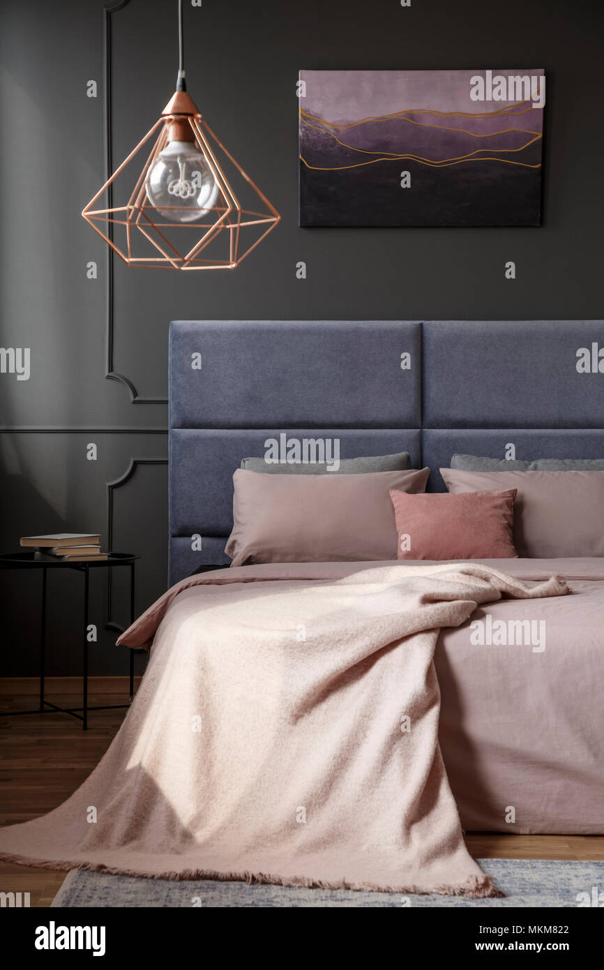 Lampada oro sopra il letto in camera da letto eleganti interni con violetta dipinto sul muro grigio Foto Stock