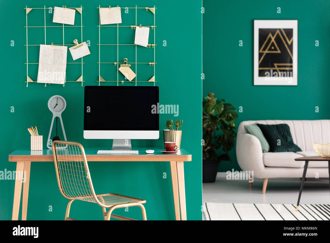Spazio di studio e home office con computer su una scrivania di legno in un moderno soggiorno interno con pareti verdi Foto Stock