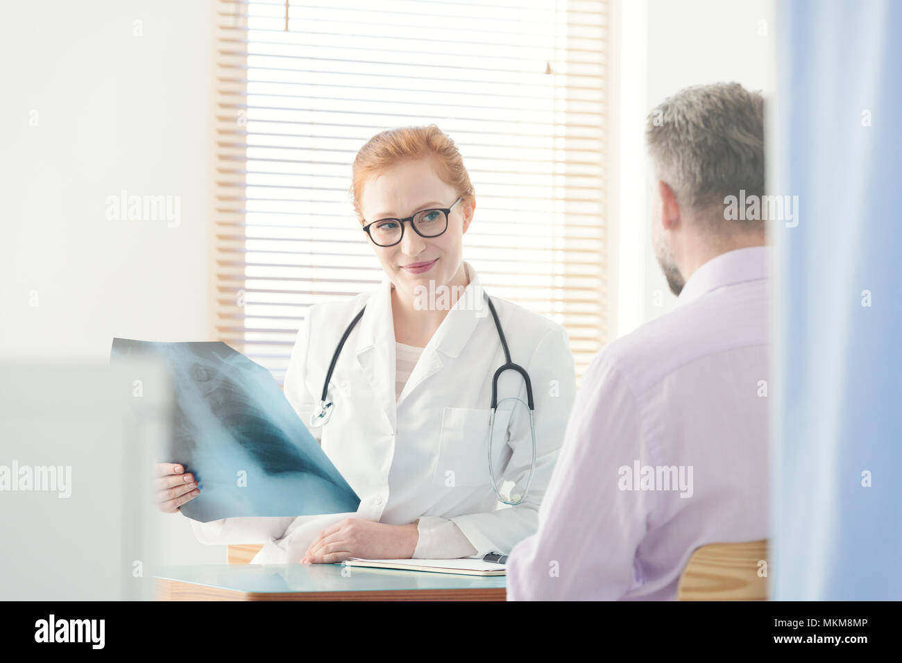 Sorridente pulmonologist guardando un'immagine a raggi x durante il colloquio medico Foto Stock