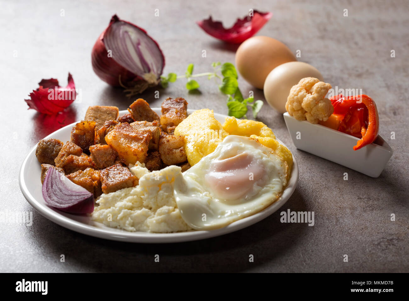 Tradizionale cibo Rumeno "Tochitura Moldoveneasca' fatta con carne di maiale, uova e formaggio con polenta sulla piastra Foto Stock