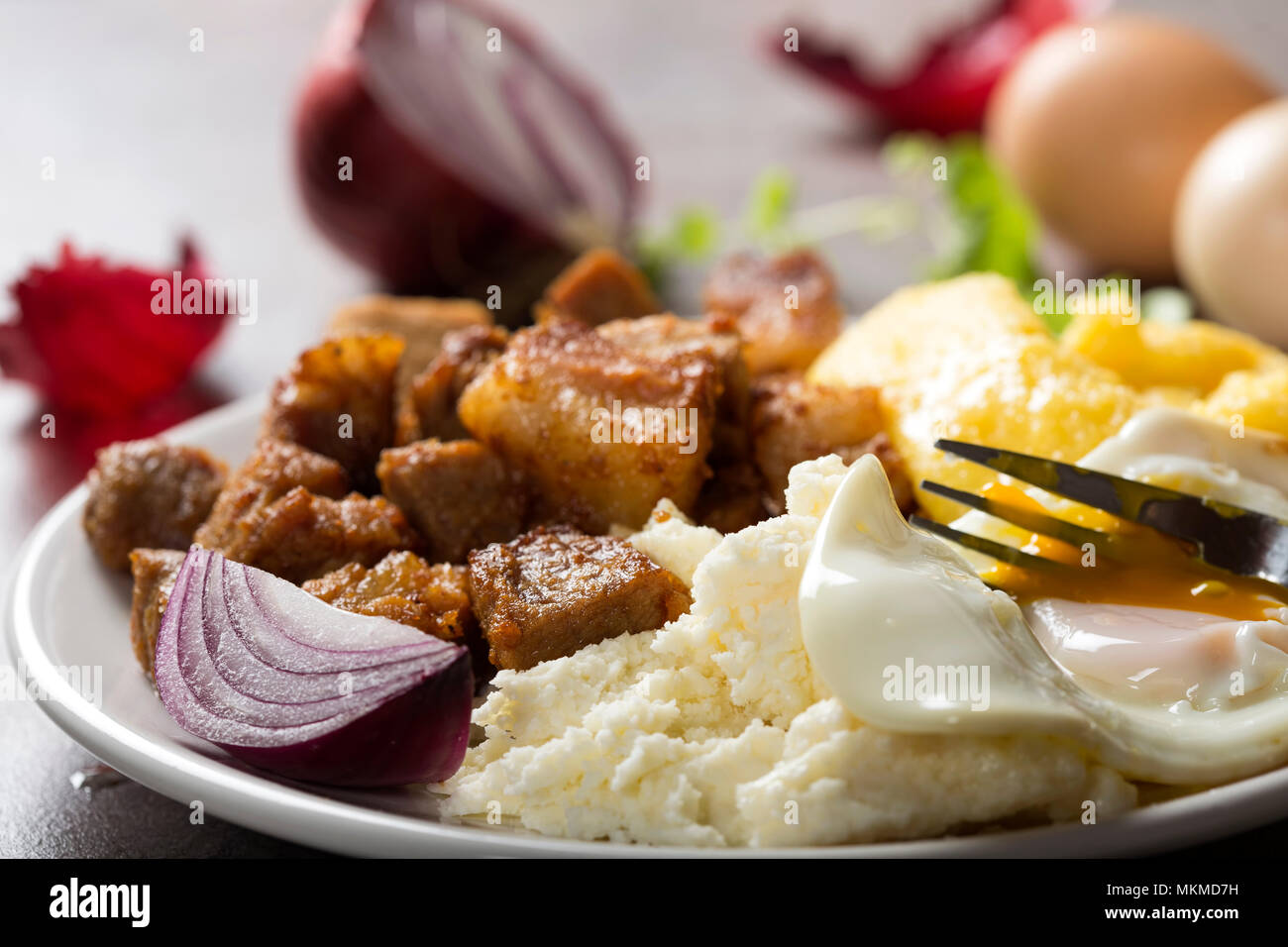 Tradizionale cibo Rumeno "Tochitura Moldoveneasca' fatta con carne di maiale, uova e formaggio con polenta sulla piastra Foto Stock