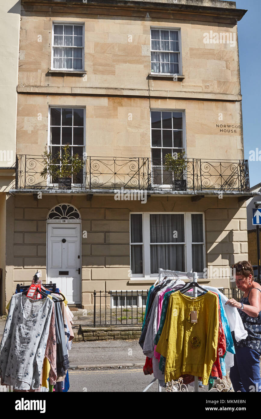 Donna che guarda di abbigliamento in Suffolk di mercato con un periodo regency house in background, vicino alla strada di Bath e Leckhampton, Cheltenham. Foto Stock