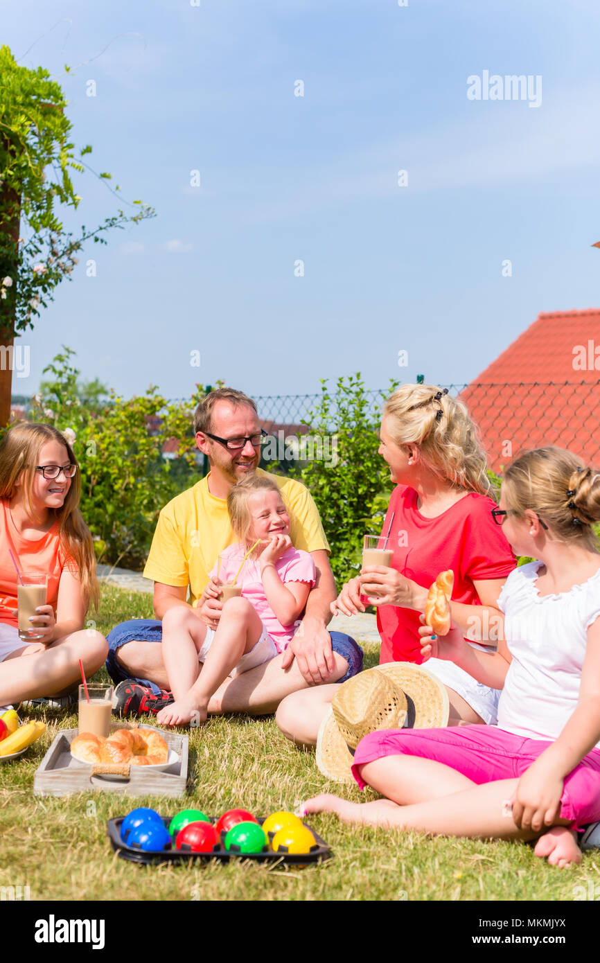 Famiglia avente picnic nel giardino davanti a casa loro Foto Stock