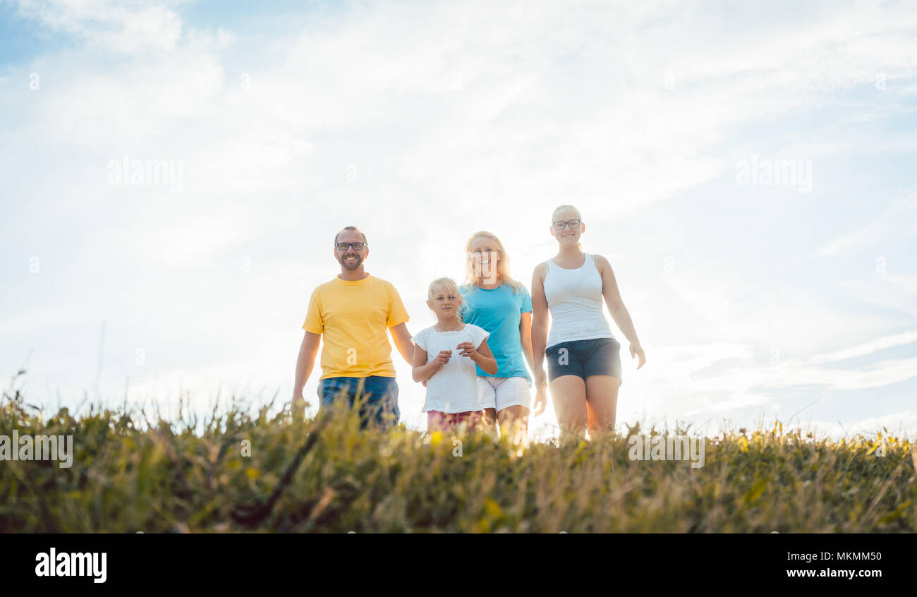 Famiglia passeggiate nel tramonto su un prato estivo Foto Stock