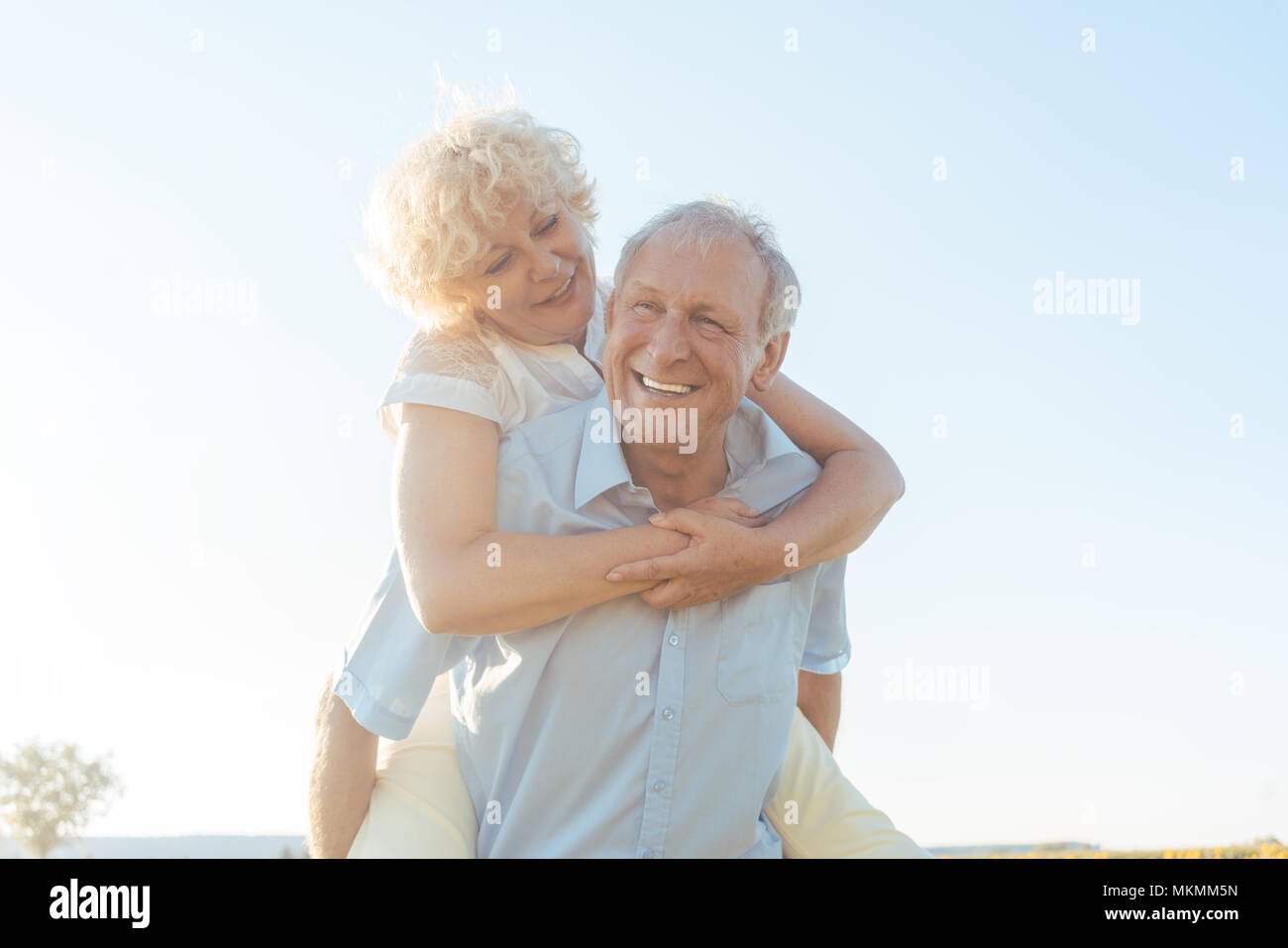 Felice l'uomo senior di ridere mentre si sta portando il suo partner sulla schiena Foto Stock