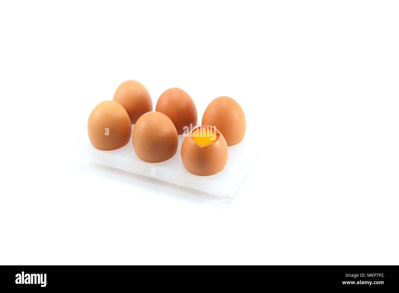 Marrone rotto le uova di gallina con uova incrinate e tuorlo su sfondo bianco. Un pacchetto di sei il pollo crudo uova per il pasto o altri alimenti per la salute. Foto Stock