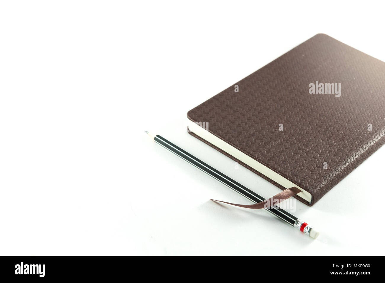 Marrone diario di notebook con matita nera su sfondo bianco Foto Stock