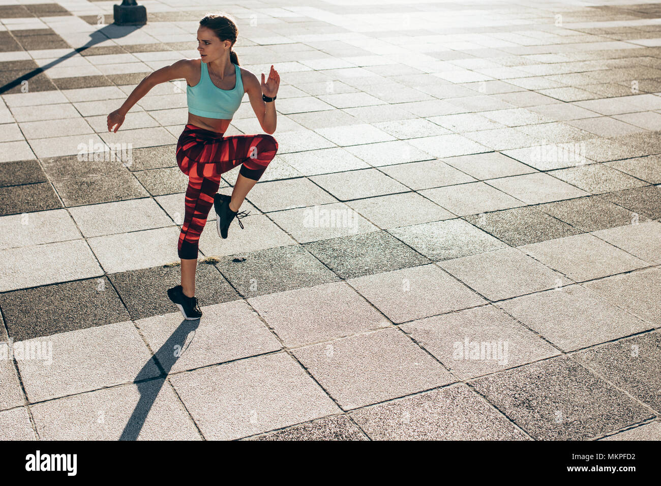 Runner affondo facendo allenamento. Lunghezza completa di sani di sesso femminile che esercitano e saltando all'aperto nella città. Foto Stock