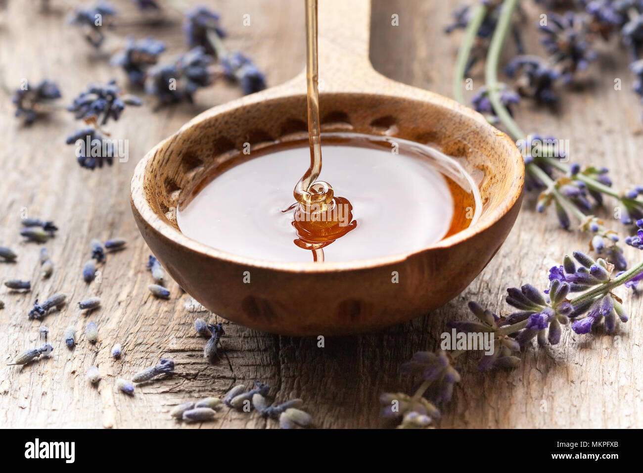 Miele di fresco in un cucchiaio di legno e lavanda sul vecchio sfondo di legno Foto Stock