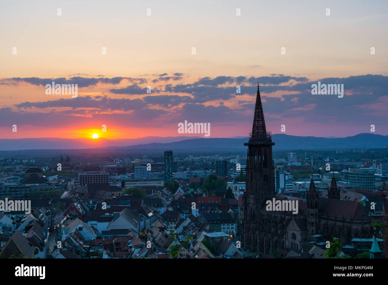 Germania, rosso tramonto dietro i monti Vosges sulla città Freiburg im Breisgau Foto Stock