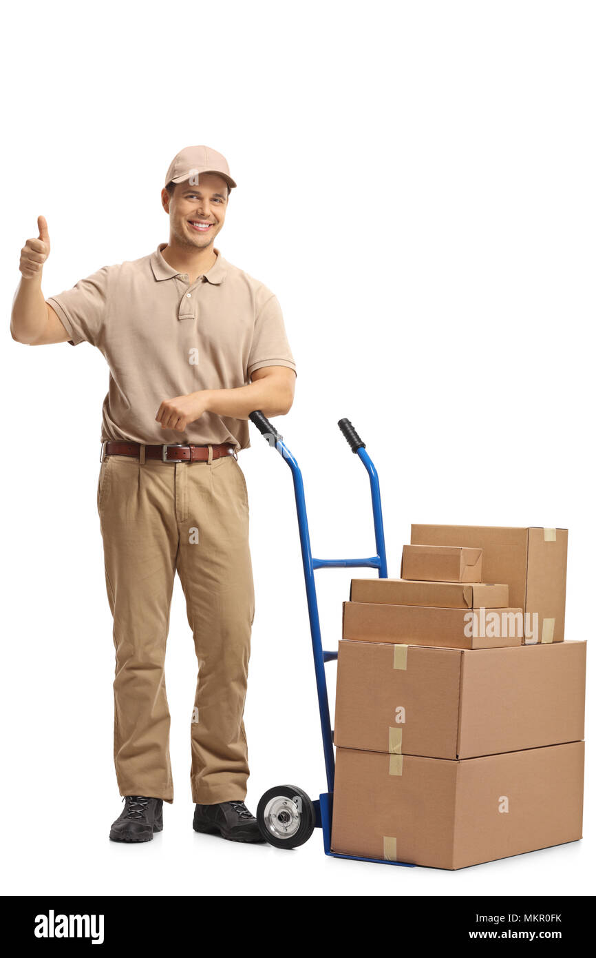 A piena lunghezza Ritratto di un uomo di erogazione con una mano carrello caricato con scatole facendo un pollice in alto segno isolato su sfondo bianco Foto Stock