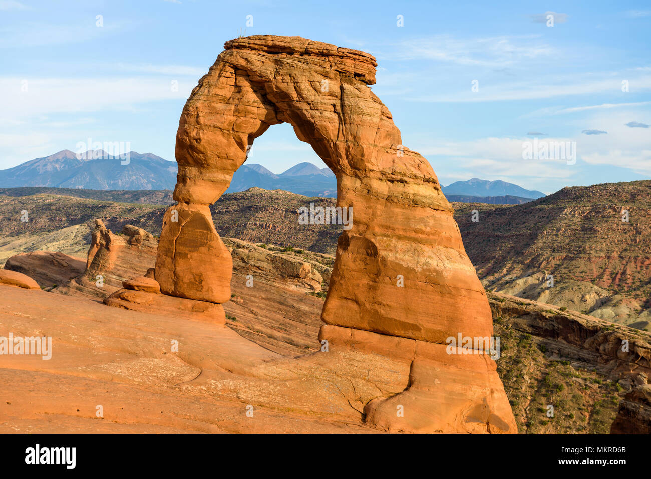 Tramonto al Delicate Arch - Una vista ravvicinata di colorati Delicate Arch in bright sole serale, con laminazione montagne rocciose in background, archi Nat Foto Stock