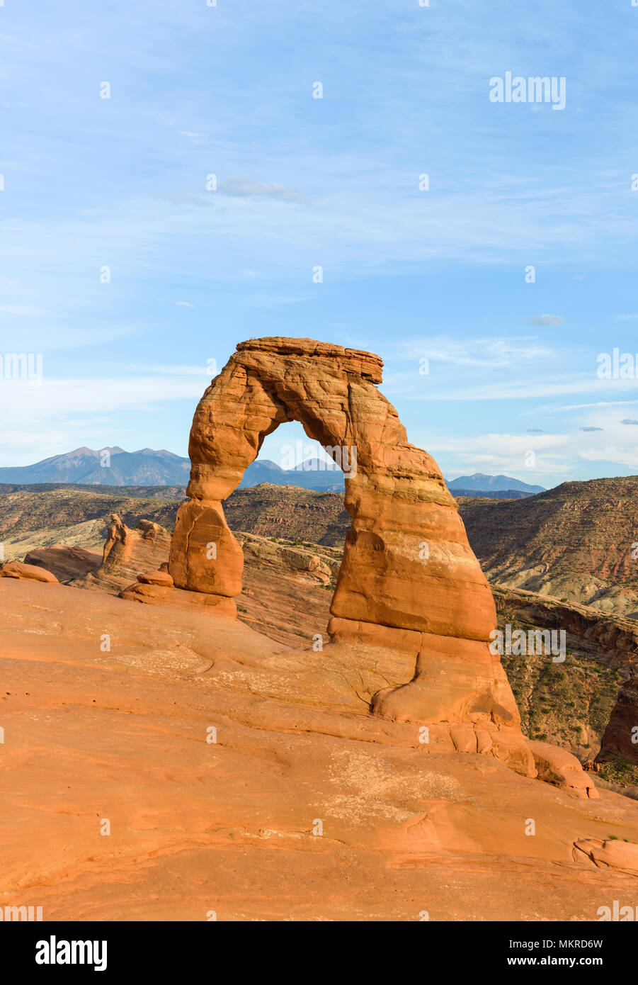 Tramonto al Delicate Arch - verticale - colorata Delicate Arch in bright sole serale, con laminazione montagne rocciose in background, Arches National Park. Foto Stock