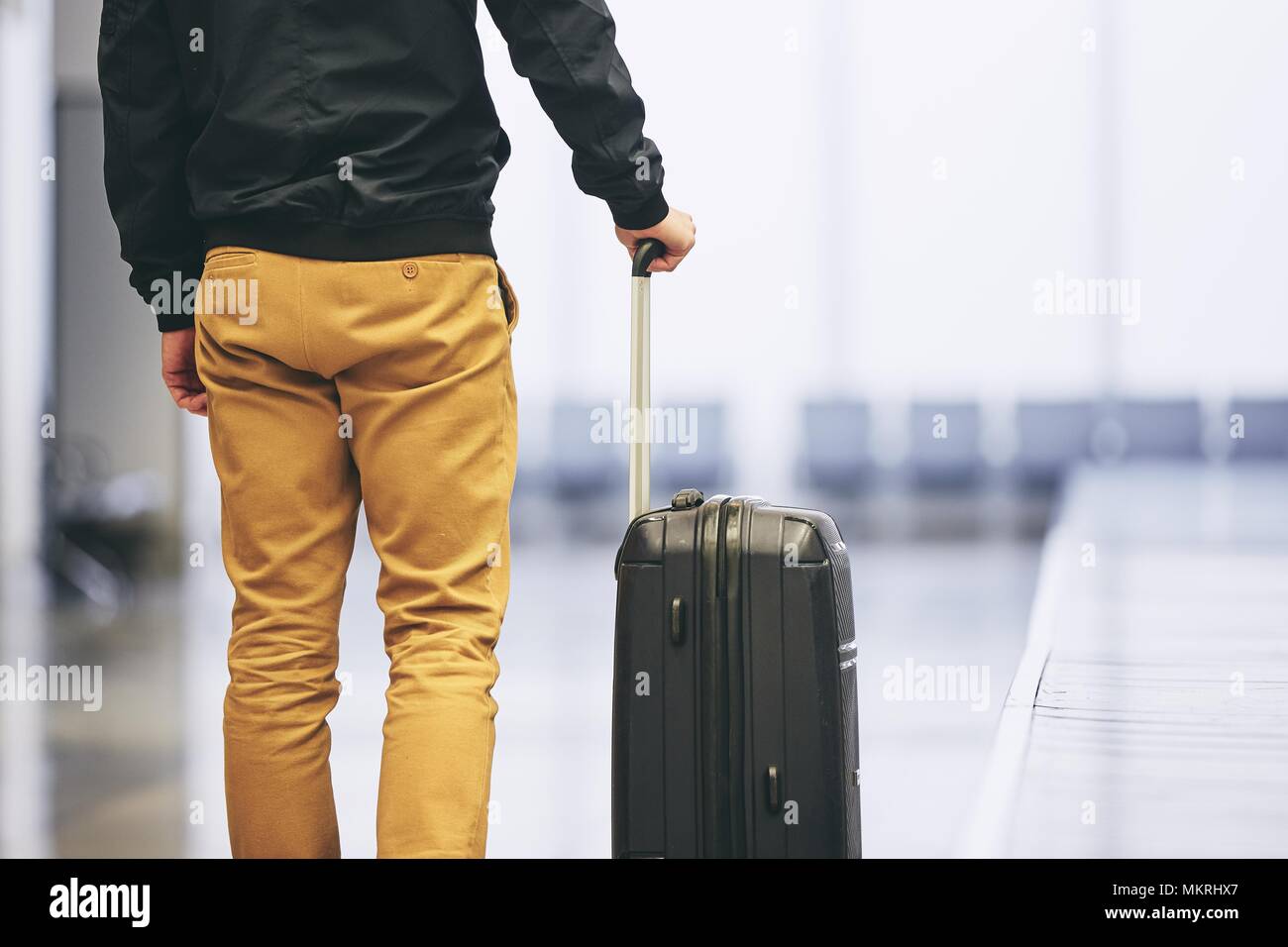 Uomo di viaggiare in aereo. Giovane passeggero tenendo la sua valigia in aeroporto. Foto Stock