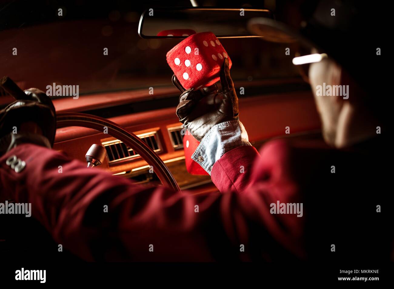 Casino Lucky desiderio concetto. Casinò Poker Player parlando a suo fortunato dadi rossi all'interno dell'auto classica. Foto Stock