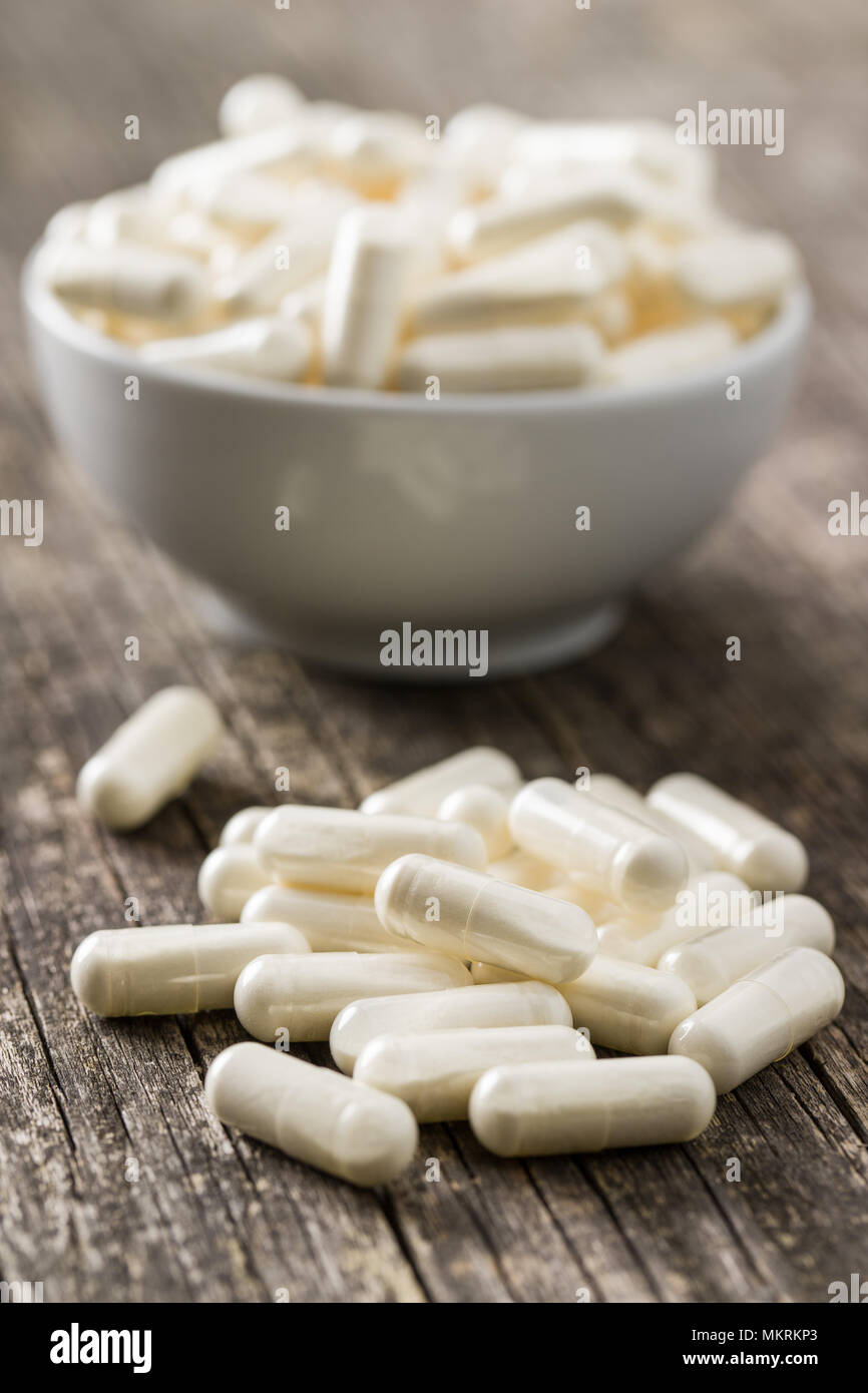 Medicina bianco capsule sul vecchio tavolo in legno. Foto Stock