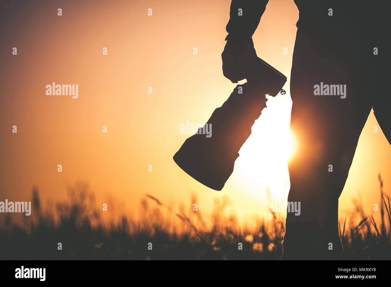 Safari fotografo Esterni al tramonto. Silhouette di uomini mantenendo la fotocamera digitale in mano con grande un teleobiettivo per la fauna selvatica meglio approfondimento. Foto Stock