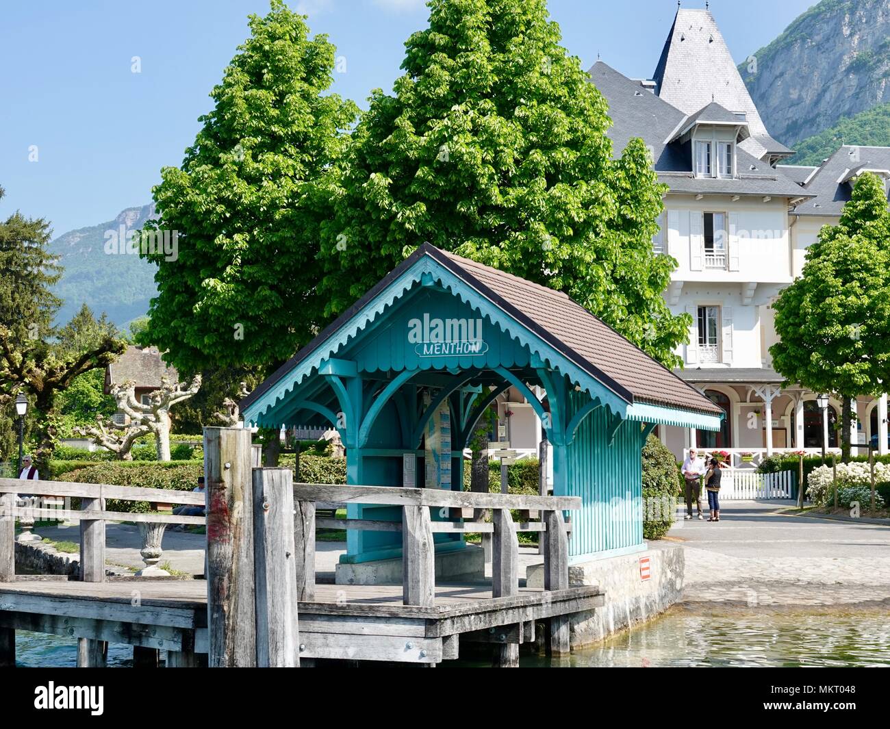 Le persone di fronte a un pittoresco hotel vicino a un bel po' di dock coperto sulle rive del lago di Annecy nelle Alpi francesi, Menthon-Saint-Bernard,Francia Foto Stock