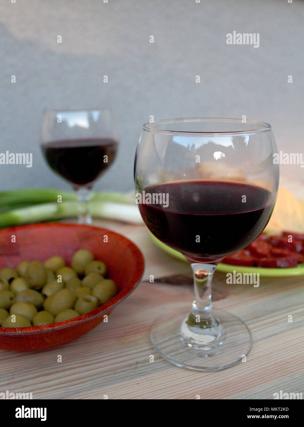 Degustazione di vini - due bicchieri di vino rosso con salsiccia tagliata a fette, formaggio, olive e cipolla Foto Stock
