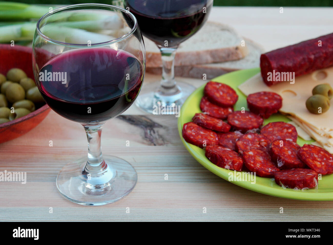 Ristoro per gli ospiti di celebrazione - bicchieri di vino rosso e fette di salame e formaggio con le olive verdi Foto Stock