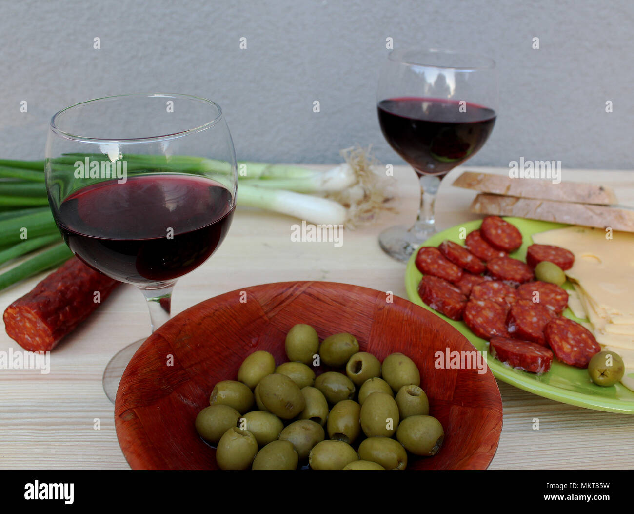 Degustazione di vini - due bicchieri di vino rosso su un tavolo con il cibo - olive verdi e fette di salame e formaggio Foto Stock