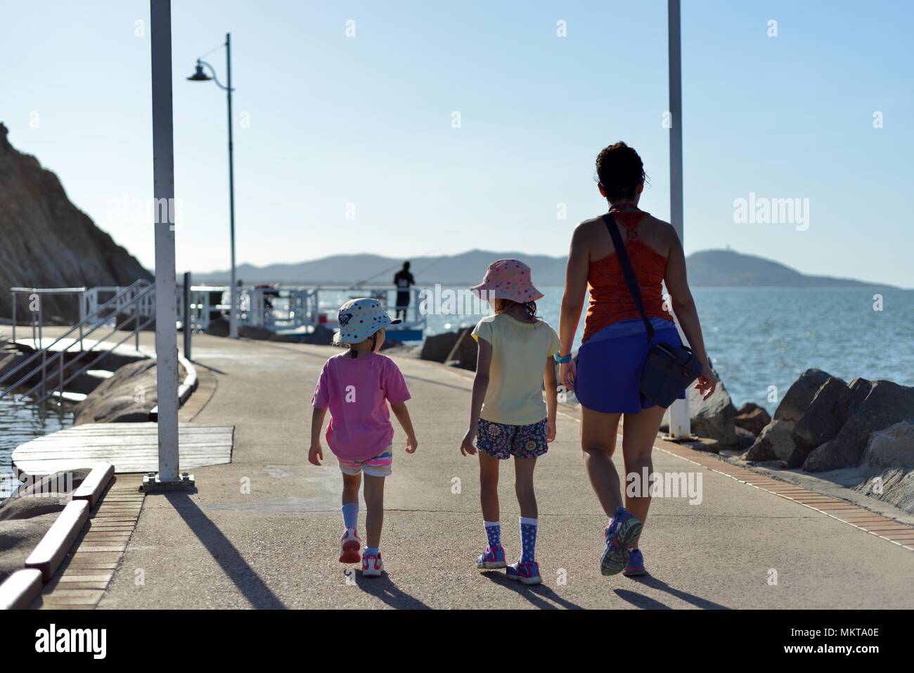 Madre e bambini camminare insieme nel tardo pomeriggio intorno al rockpool, Jezzine caserma, il kissing point fort, Townsville Queensland, Australia Foto Stock