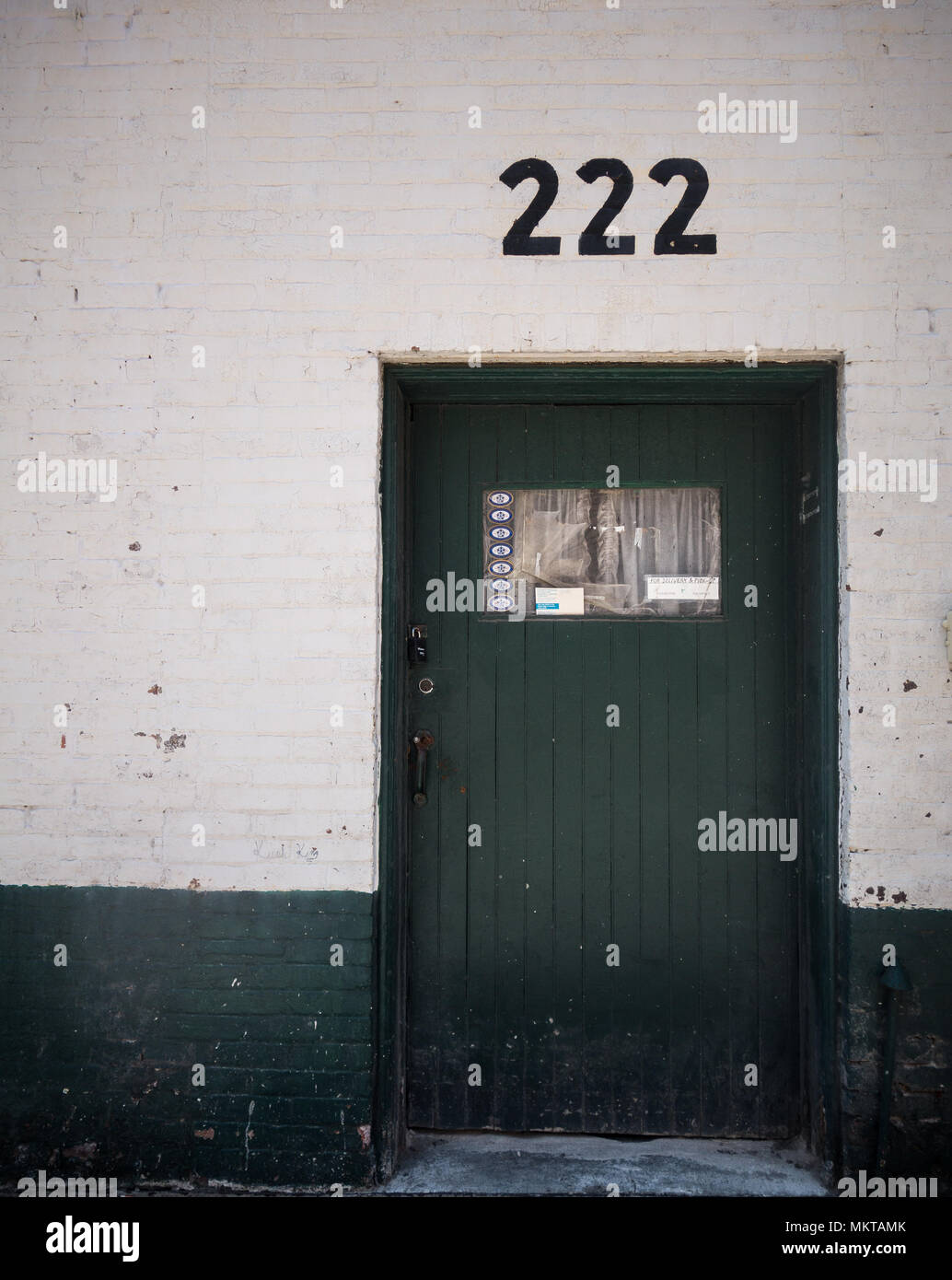 Una porta verde su un muro bianco con il numero "222" al di sopra di esso Foto Stock