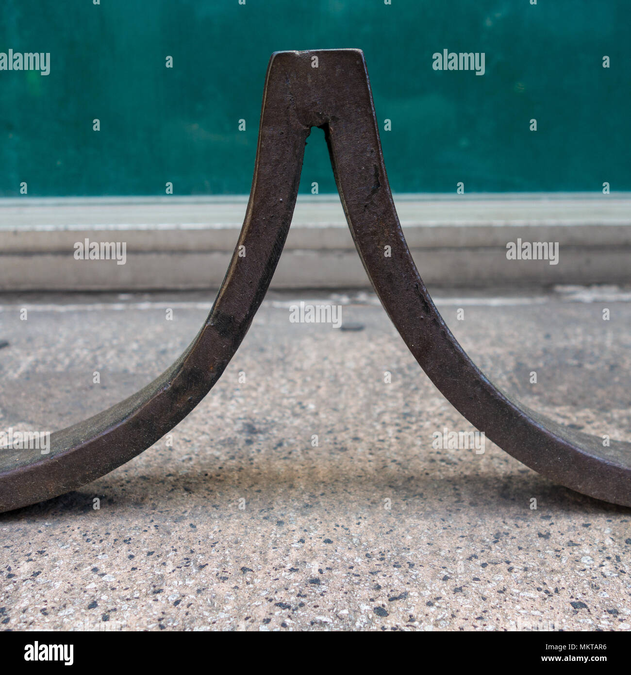 Un pezzo di metallo curvato su un marciapiede della città che forma un picco su Foto Stock