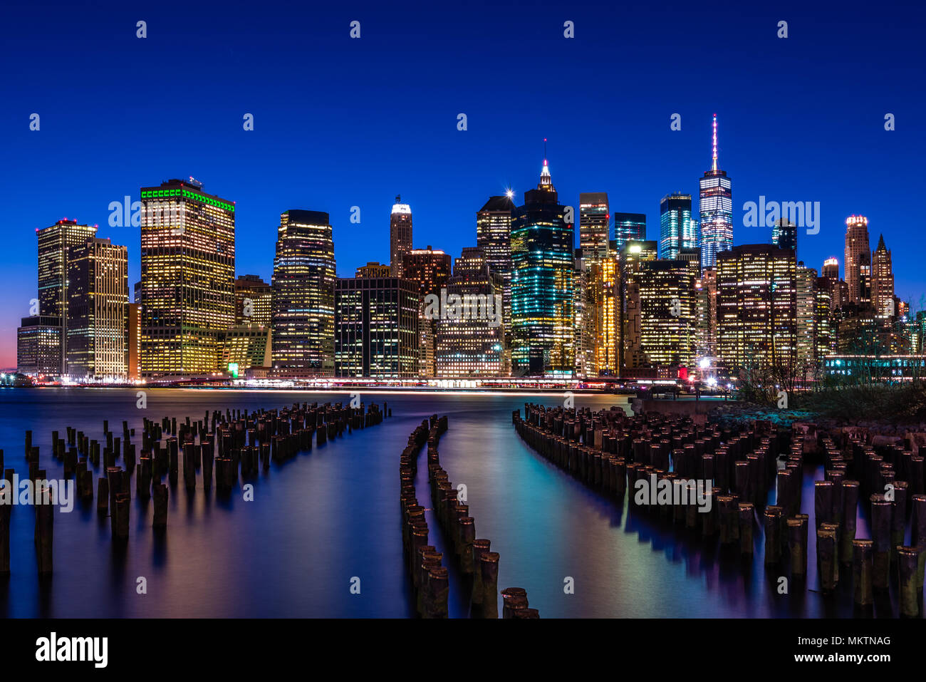 La skyline di New York in cerca di fronte al Ponte di Brooklyn Park attraverso i resti delle vecchie banchine Foto Stock