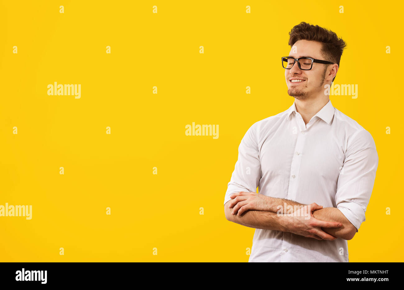 Bello Casual Uomo in camicia bianca e occhiali tenendo le mani insieme e godendo di stato pacifico della mente. Foto Stock