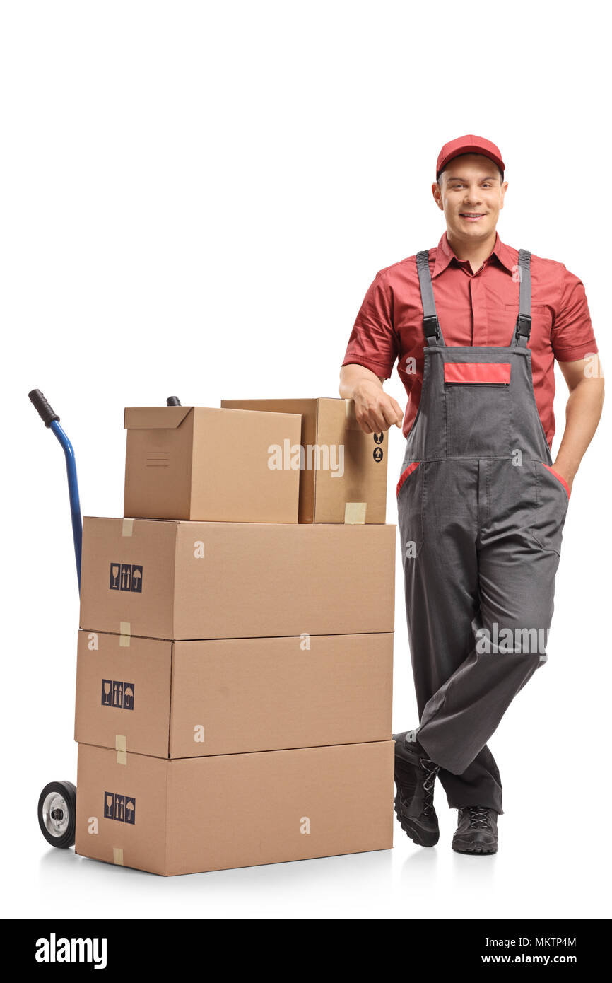 A piena lunghezza Ritratto di un mover appoggiato su una pila di scatole caricati su un carrello elevatore a mano isolati su sfondo bianco Foto Stock