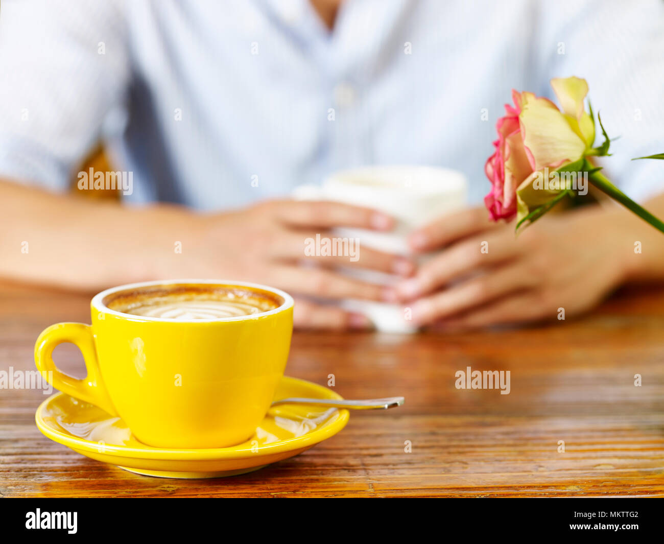 Giovane uomo in una conversazione mentre si beve il caffè o il tè, concentrarsi sulla tazza di cappuccino. Foto Stock
