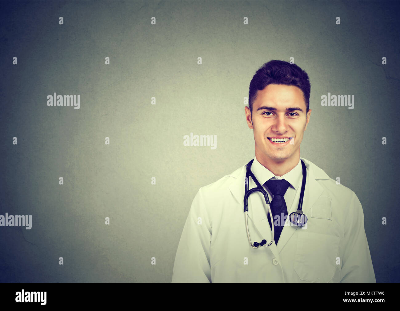 Ritratto di un sorridente medico maschio sul muro grigio sfondo Foto Stock