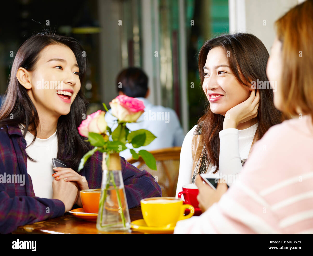 Tre felice giovane e belle donne asiatiche seduta a tavola in chat parlando in negozio di caffè o di tè casa. Foto Stock