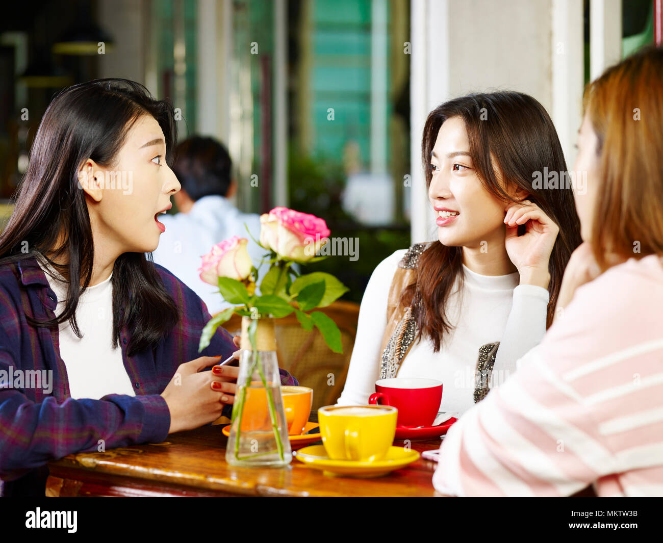 Tre felice giovane e belle donne asiatiche seduta a tavola in chat parlando in negozio di caffè o di tè casa. Foto Stock